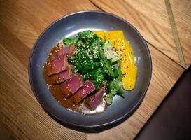 frisch hell saftig Thunfisch und Mango Salat mit Spinat auf ein schön grau Teller foto