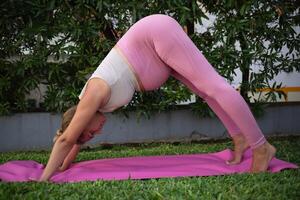 jung schön schwanger Frau Praktiken Methoden Ausübungen Yoga Asanas auf das Grün Rasen draußen. Achtsamkeit und gesund Lebensstil Konzept foto