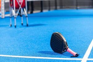 schwarz Fachmann Paddel Tennis Schläger und Ball mit natürlich Beleuchtung auf Blau Hintergrund. horizontal Sport Thema Poster, Gruß Karten, Überschriften, Webseite und App foto