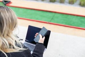 Frau auf Golf Kurs mit Smartphone mit Sport Wetten App foto