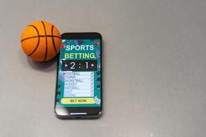 Smartphone mit Anwendung zum Sport Wetten und ein Basketball Ball, Konzept von online Wetten foto