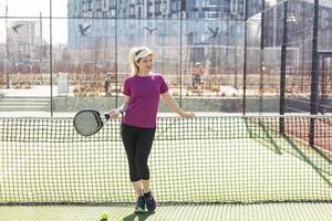 aktiv jung Frau versuchen zu schlagen das Ball durch Padel Schläger während spielen Tennis im das Gericht foto