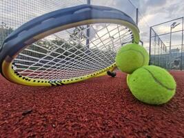 Gelb Tennis Bälle und Schläger auf schwer Tennis Gericht Oberfläche, oben Aussicht Tennis Szene foto