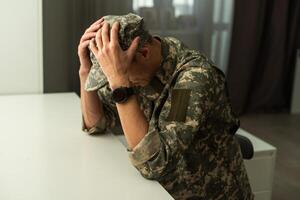 ein verstört Soldat Abdeckung seine Gesicht, möglicherweise Leiden von Schale Schock oder Post traumatisch Stress Störung foto