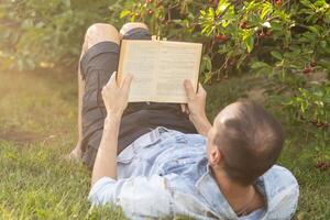ein Mann liest das Bibel auf das Gras beim ein Park foto