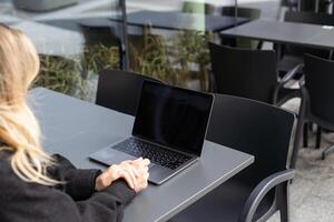 jung Frau Sitzung auf online Treffen im draussen Cafe, reden zu Laptop Kamera, erklären etwas, Trinken Kaffee. foto