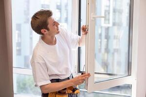 ein Handwerker Instandsetzung, passt sich an oder installiert Metall-Kunststoff Fenster im das Wohnung. Verglasung von Balkone, Loggien, Veranden im Haus. Produktion von doppelt verglast Fenster zu Individuell Größen foto