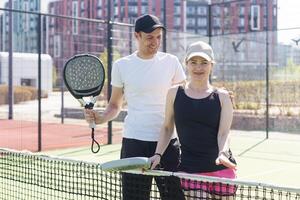 Sport Paar mit Padel Schläger posieren auf Tennis Gericht foto