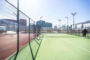 landschaftlich gestaltet Bereiche von ein Wohn Entwicklung mit ein Tennis Gericht mit hoch Plexiglas und Metall Zäune foto