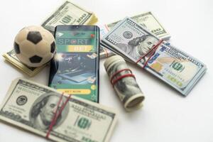 Smartphone mit Glücksspiel Handy, Mobiltelefon Anwendung und Fußball Ball mit Geld Nahansicht. Sport und Wetten Konzept foto