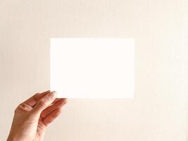 Hand halten ein leer Weiß Karte gegen ein neutral Hintergrund foto