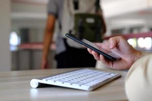 Nahaufnahme der Hände eines Mannes, die mit einem Smartphone aufgenommen wurden, im Café ist ein Mann an seinem Telefon und tippt Nachrichten in sozialen Medien ein. foto