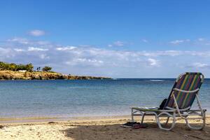 Chaise Salon auf das Meer Sand auf das Küste von das azurblau Meer und gegen das Blau Himmel, das Konzept von Entspannung auf ein tropisch Insel foto