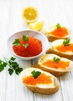 roter Kaviar in Schüssel und Sandwiches foto