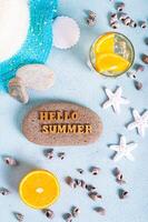 Hallo Sommer- Text auf Stein, Hut, Cocktail, orange, Seestern und Muscheln auf Blau oben und Vertikale foto