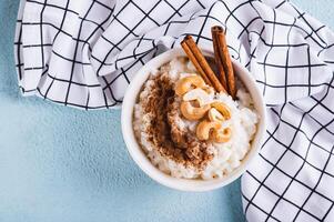 schließen oben von Reis Pudding mit Zimt und Cashewkerne im ein Schüssel auf das Tabelle oben Aussicht foto