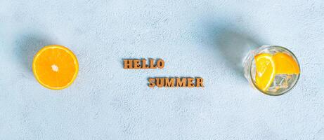 Konzept Hallo Sommer- Text, Hut, Cocktail und Hälfte ein Orange auf Blau Hintergrund oben Aussicht Netz Banner foto