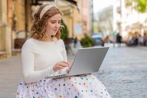 Frau Freiberufler Arbeiten online entfernt Job mit Laptop Sitzung im Stadt Straße Surfen Webseite foto