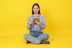 jung asiatisch Frau mit Tablette auf Gelb Hintergrund foto