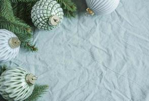 Fichtenzweige mit Weihnachtsschmuck auf dem grünen Leinen zerknitterten Textilhintergrund foto