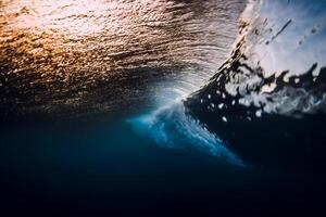 Welle Absturz im Ozean mit Sonnenuntergang oder Sonnenaufgang Licht. unter Wasser Aussicht von Surfen Welle foto