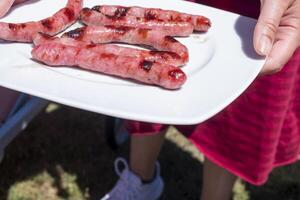 selektiv Fokus, ein Frau halten ein Teller von gegrillt Würste foto