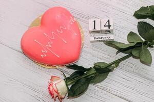 Rosa Tee Rose mit Herz geformt Rosa Mousse Kuchen und Februar 14 Kalender. foto