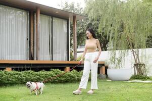 glücklich asiatisch Frau spielen mit süß Clever Mops Hündchen Hund im das Hinterhof foto