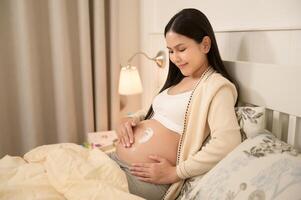 schön schwanger Frau bewirbt sich feuchtigkeitsspendend, strecken Kennzeichen Sahne auf Bauch, Fruchtbarkeit Unfruchtbarkeit Behandlung, In-vitro-Fertilisation, Zukunft Mutterschaft Konzept foto