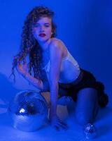 jung Frau mit Disko Ball ist posieren im Musik- Stil, Party machen im Nachtclub Blau Neon- farbig Beleuchtung foto