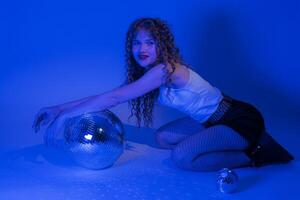 Frau posieren im Blau Neon- farbig Beleuchtung während Nachtclub Party, halten Spiegel Disko Ball foto