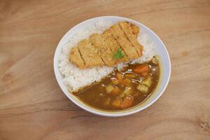 Reis mit Curry und Hähnchen Schnitzel im Weiß Schüssel auf hölzern Tabelle foto