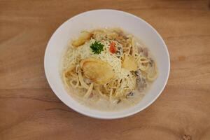 Spaghetti mit Pilz Soße und Käse im Weiß Schüssel auf hölzern Tabelle foto