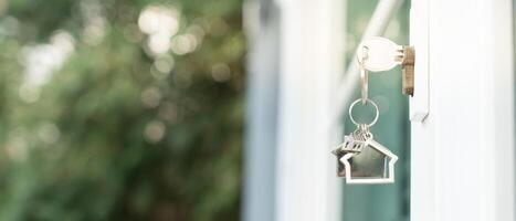 Vermieterschlüssel zum Aufschließen des Hauses steckt in der Tür. Haus aus zweiter Hand zu vermieten und zu verkaufen. Schlüsselbund weht im Wind. hypothek für neues zuhause, kaufen, verkaufen, renovieren, investition, eigentümer, nachlass foto