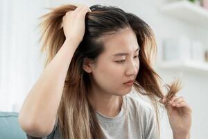 asiatisch Frau sehr traurig und verärgert suchen beim beschädigt Haar, Haar Verlust, Haar Verdünnung Problem, Vitamin Mangel, Kahlheit, nach der Geburt, Biotin, Zink, Menstruation- oder endokrine Störungen, hormonell Ungleichgewicht foto