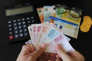 das Papier Währung von Truthahn. Taschenrechner im das Hintergrund.Türkisch Lira Banknoten. Mann Zählen Türkisch Geld mit seine Hand. foto
