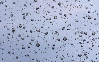 Regentropfen auf Glas Fenster von Auto mit wolkig Himmel im das Hintergrund foto