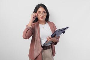 schick asiatisch Frau halten dokumentieren auffällig Modell- Pose berühren Brille isoliert durch Weiß Hintergrund. foto