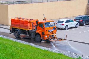 Bewässerung Maschine das Orange Farbe wäscht das Straße Staub und Schmutz foto