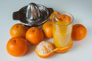 Glas von gesund frisch Saft von Mandarinen und Handbuch Entsafter auf Weiß Hintergrund foto