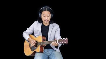 asiatisch Künstler Singen Lied und spielen akustisch Gitarre auf schwarz Hintergrund zum Leben akustisch Konzert und Musik- verbunden foto