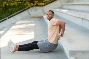 erfolgreich spanisch Sportler tun verschiedene physisch Übungen, Morgen trainieren beim das Stadion, Mann motivierend lächelnd und suchen beim das Kamera, Athlet im das Luft Fitness. foto