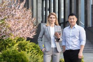 Porträt von vielfältig Geschäft Gruppe, asiatisch Mann und Frau im Geschäft Anzüge suchen beim Kamera und lächelnd, zwei Arbeitskräfte draußen Büro foto