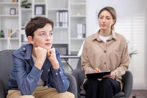 ein pädiatrisch Psychologe berät ein Teenager Junge, Arbeiten Innerhalb ein medizinisch Beratung Zimmer. foto