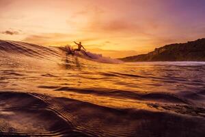 Dezember 14, 2022. Bali, Indonesien. Mann während Surfen mit Sonnenuntergang Töne. Profi Surfer Reiten auf Welle und machen Tricks. foto
