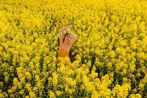 Antenne Aussicht von attraktiv Frau beim Blühen Raps Feld. Blumen und glücklich Frau foto