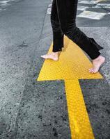 barfuß auf das Asphalt. nackt Damen Füße auf das Hintergrund von Straße Markierungen. foto