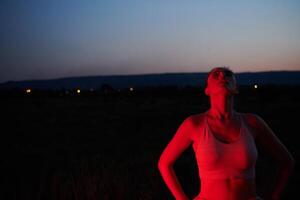 Athlet Streiks ein Pose im rot beleuchtet Nachtzeit glühen foto