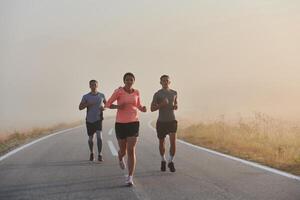 ein Gruppe von Freunde, Sportler, und Jogger Umarmung das früh Morgen Std wie Sie Lauf durch das neblig Dämmerung, erregt durch das steigend Sonne und umgeben durch das still Schönheit von Natur foto