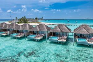 luftaufnahme der malediveninsel, des luxuriösen wasservillenresorts und des holzstegs. schöner himmel und ozeanlagune strandhintergrund. Sommerferien Urlaub und Reisekonzept. paradies luftlandschaft pano foto